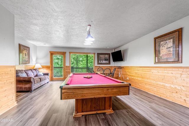 recreation room featuring wainscoting, a textured ceiling, wood finished floors, wood walls, and billiards table