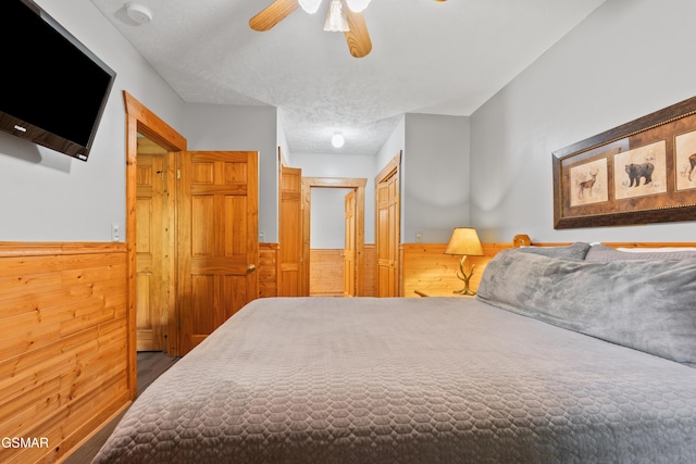 bedroom with wainscoting, wooden walls, a ceiling fan, wood finished floors, and a closet