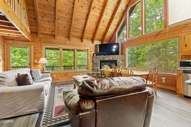 living room featuring healthy amount of natural light, wooden ceiling, wooden walls, beamed ceiling, and a fireplace