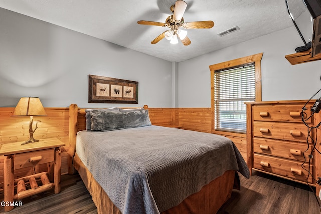 bedroom with dark wood-style flooring, wainscoting, wood walls, and ceiling fan