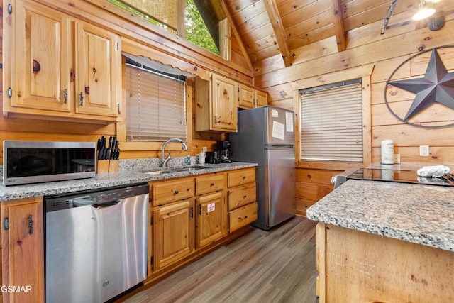 kitchen featuring stainless steel appliances, a sink, wood walls, wood ceiling, and light wood finished floors