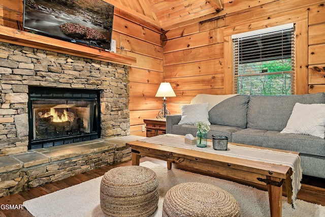 living area with vaulted ceiling, wood finished floors, wood walls, a stone fireplace, and wooden ceiling