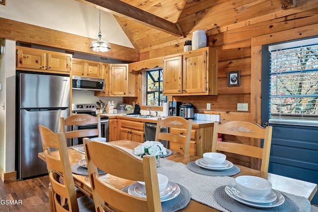 kitchen with appliances with stainless steel finishes, wooden walls, dark wood-type flooring, beamed ceiling, and pendant lighting