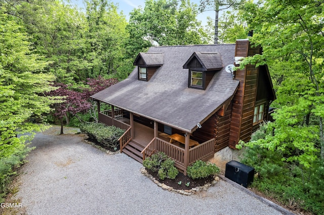 view of front of home with a chimney, covered porch, and roof with shingles