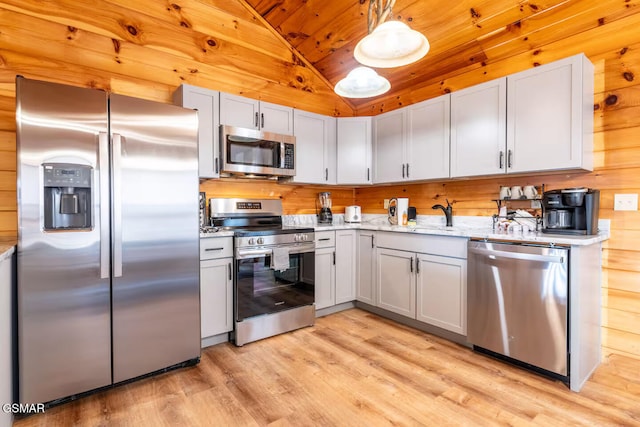 kitchen with light wood-style floors, vaulted ceiling, wood ceiling, appliances with stainless steel finishes, and wood walls