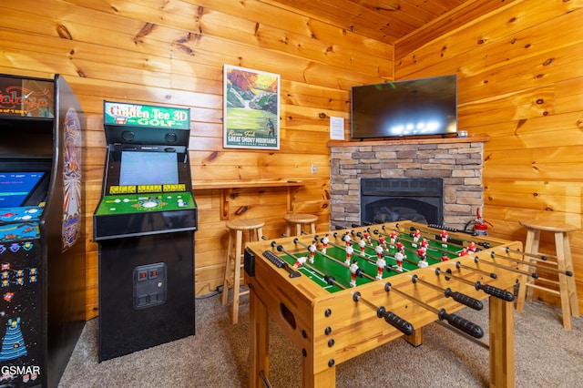 rec room featuring wood walls, a stone fireplace, and carpet