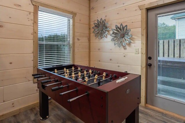 rec room with hardwood / wood-style flooring, a healthy amount of sunlight, and wood walls