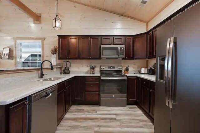 kitchen featuring sink, light hardwood / wood-style flooring, lofted ceiling with beams, pendant lighting, and appliances with stainless steel finishes