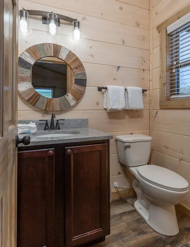 bathroom featuring hardwood / wood-style flooring, toilet, and wood walls