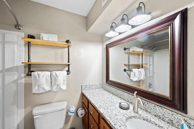 bathroom featuring a shower, vanity, and toilet