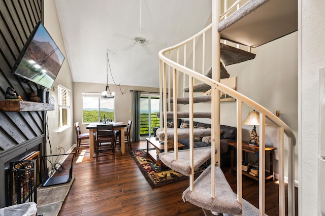 staircase with hardwood / wood-style flooring, lofted ceiling, and an inviting chandelier