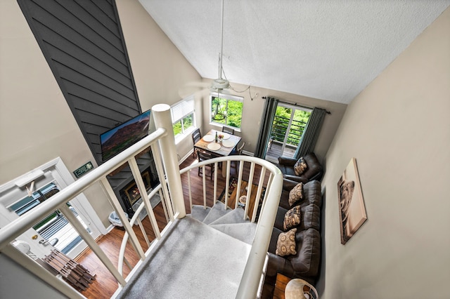 staircase featuring a textured ceiling, ceiling fan, vaulted ceiling, and hardwood / wood-style flooring