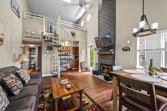 living room featuring a chandelier, a towering ceiling, a large fireplace, and dark hardwood / wood-style floors