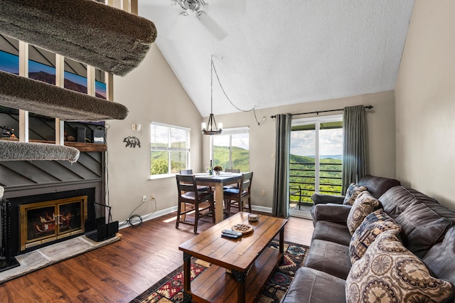 living room featuring a textured ceiling, hardwood / wood-style flooring, high vaulted ceiling, and ceiling fan