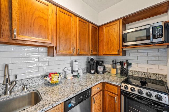 kitchen with decorative backsplash, sink, light stone counters, and stainless steel appliances