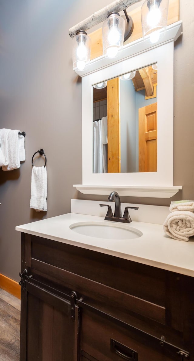 bathroom featuring hardwood / wood-style floors, vanity, and beam ceiling