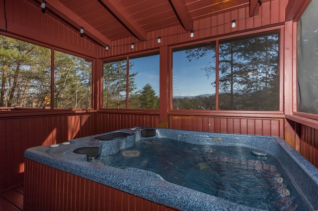 sunroom with a jacuzzi, beam ceiling, and wooden ceiling