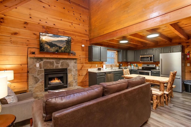 living room with wood walls, light hardwood / wood-style floors, a fireplace, beam ceiling, and wood ceiling