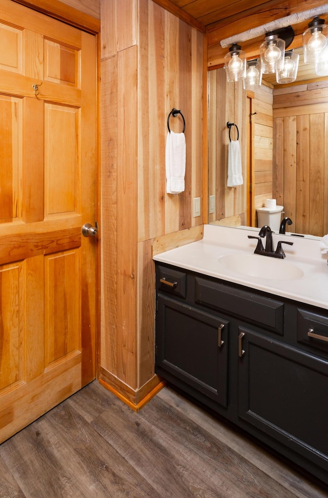 bathroom with hardwood / wood-style floors, vanity, wood walls, and toilet