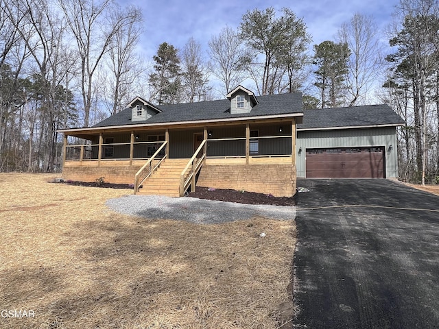 view of front of property featuring aphalt driveway, roof with shingles, a porch, and an attached garage