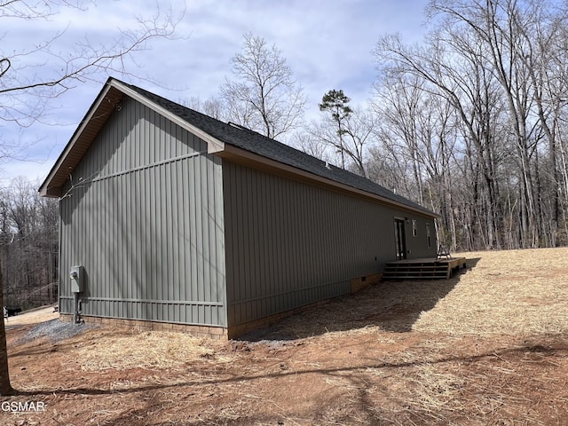 view of side of home featuring crawl space and roof with shingles