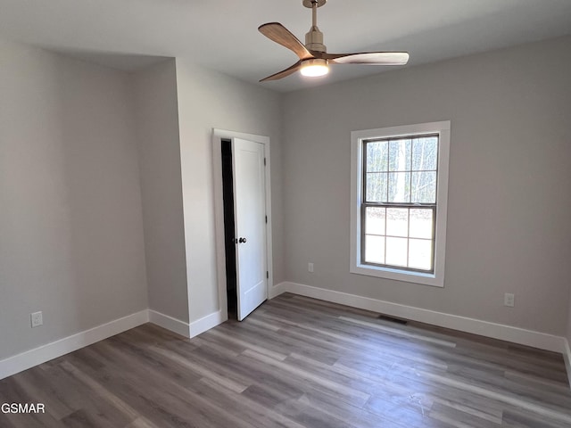 spare room with wood finished floors, baseboards, visible vents, and ceiling fan