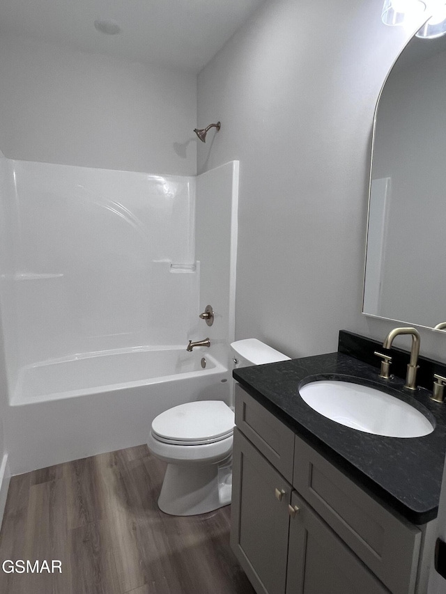 bathroom with toilet, wood finished floors, vanity, and shower / tub combination