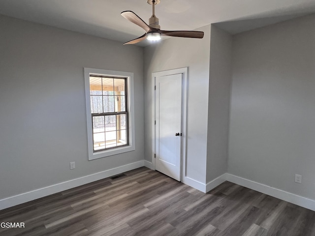 unfurnished room featuring visible vents, dark wood-type flooring, and baseboards