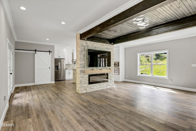 2438 Daniels Dr, Morristown, TN 37813 - unfurnished living room with a barn door, baseboards, dark wood-style floors, a stone fireplace, and beam ceiling