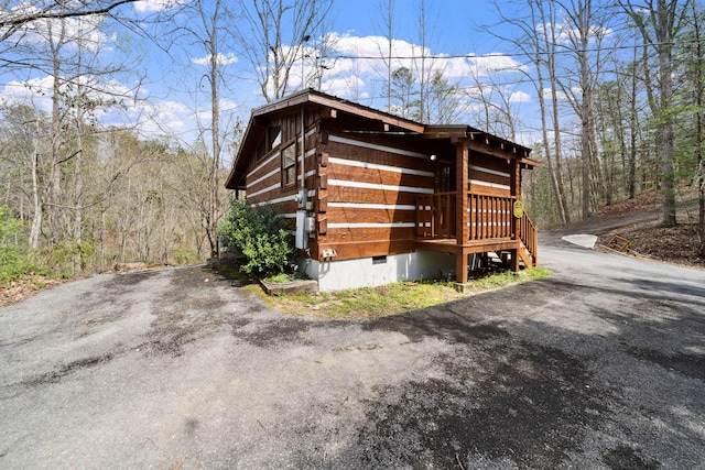 view of property exterior featuring driveway, crawl space, and log exterior