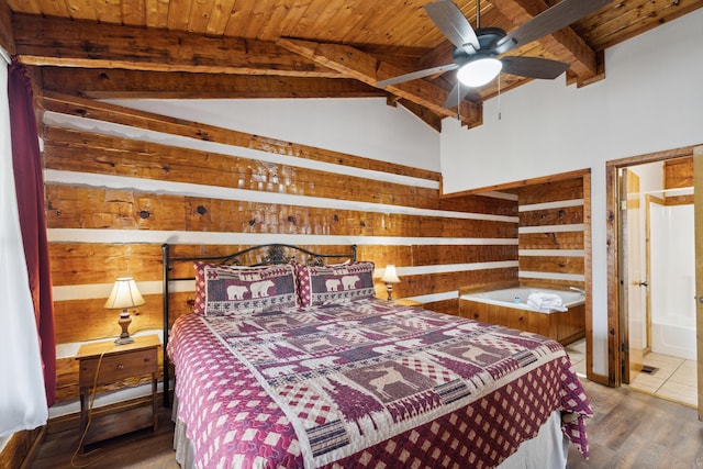 bedroom featuring wood walls, wood ceiling, connected bathroom, vaulted ceiling with beams, and wood finished floors