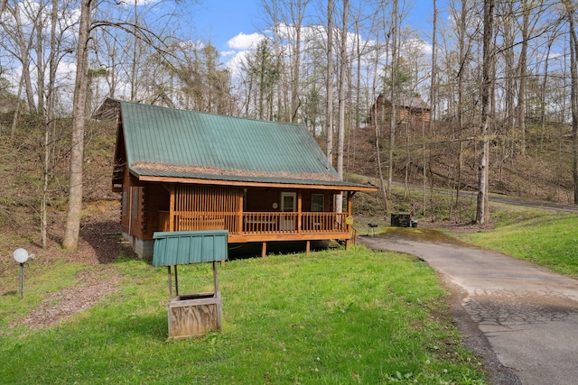 chalet / cabin with aphalt driveway, a front lawn, and metal roof