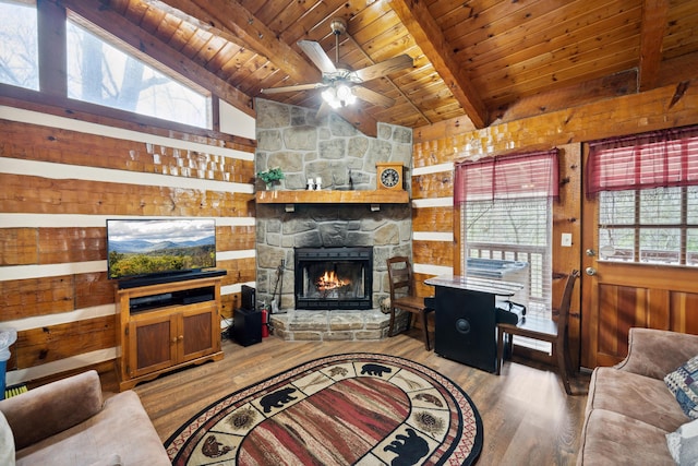 living room with a fireplace, wood finished floors, a ceiling fan, beam ceiling, and wood ceiling