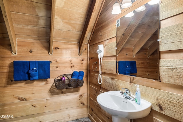 bathroom with sink, wood ceiling, vaulted ceiling with beams, and wood walls