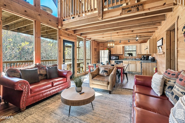 living room featuring hardwood / wood-style floors, wood walls, sink, a chandelier, and beam ceiling