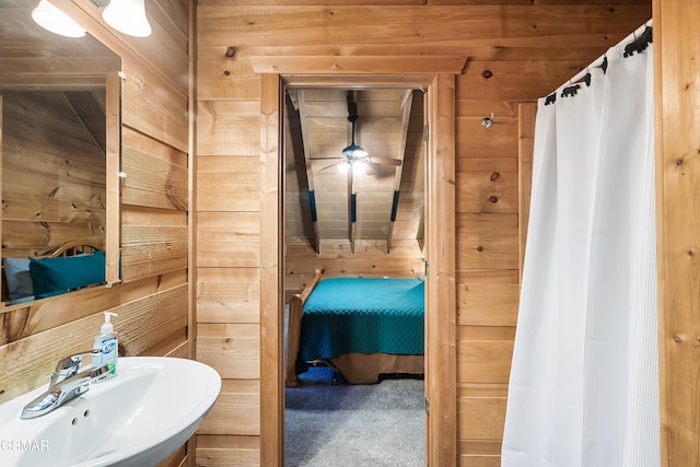 bathroom featuring sink, ceiling fan, and wood walls