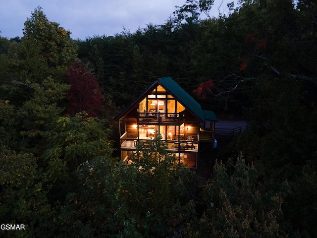 back house at dusk featuring a balcony