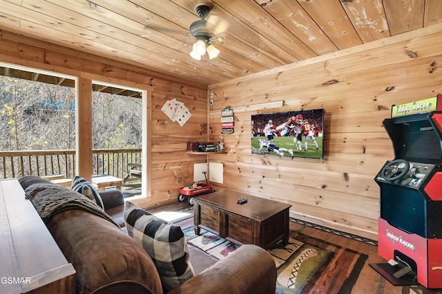 living room with ceiling fan, wooden ceiling, and wooden walls