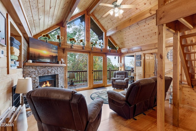 living room featuring ceiling fan, wooden walls, high vaulted ceiling, beamed ceiling, and light hardwood / wood-style floors