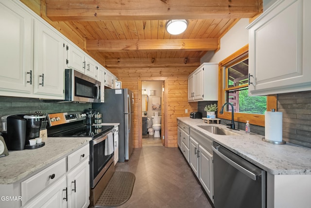3955 Millers Ridge Way, Sevierville, TN 37862 - kitchen with appliances with stainless steel finishes, a wood ceiling with exposed beams, white cabinetry, backsplash, and wood walls