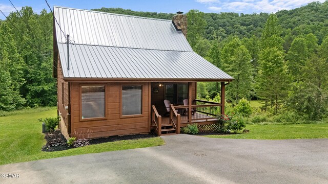 3955 Millers Ridge Way, Sevierville, TN 37862 - rustic home featuring a forest view, a chimney, a front yard, a metal roof, and a wooden deck