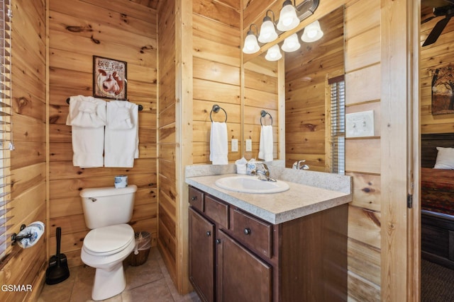 bathroom with vanity, tile patterned floors, toilet, and wood walls