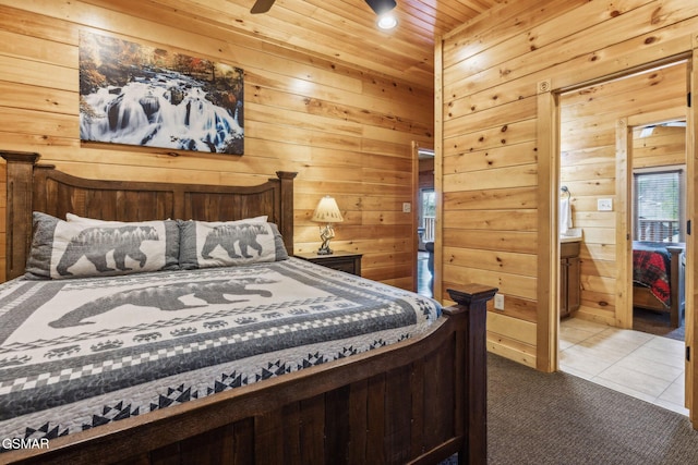 carpeted bedroom featuring tile patterned floors, wooden walls, wooden ceiling, and ensuite bathroom