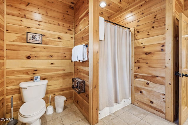 bathroom featuring tile patterned flooring, a shower with shower curtain, wooden walls, and toilet