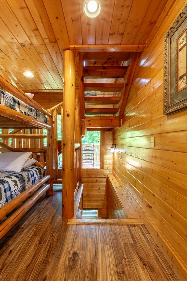 staircase with wood ceiling, wooden walls, wood-type flooring, and vaulted ceiling