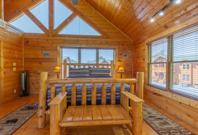 bedroom with wooden walls, light hardwood / wood-style flooring, wooden ceiling, and vaulted ceiling