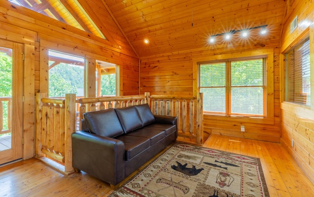 living room featuring light hardwood / wood-style floors, plenty of natural light, wood walls, and wood ceiling