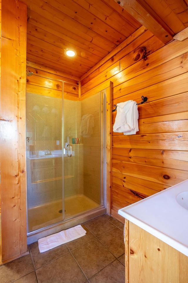 bathroom with vanity, tile patterned floors, a shower with shower door, and wood walls