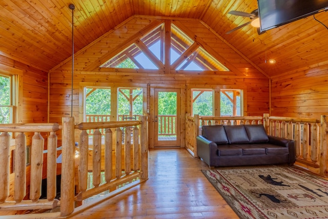 unfurnished living room featuring ceiling fan, wood ceiling, a wealth of natural light, and light hardwood / wood-style flooring