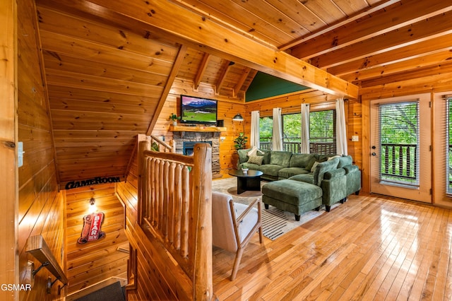 living room featuring light wood-style flooring, lofted ceiling with beams, wooden walls, a fireplace, and wood ceiling